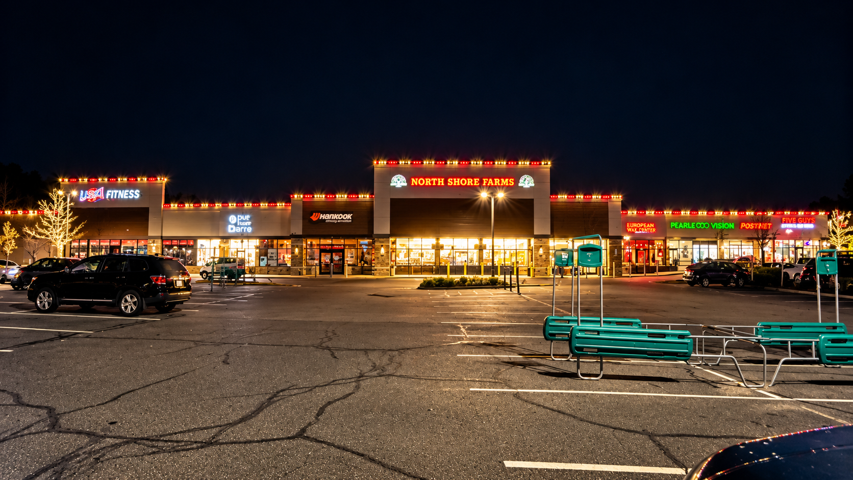 Commercial shopping plaza illuminated with festive red and white Christmas roofline lights